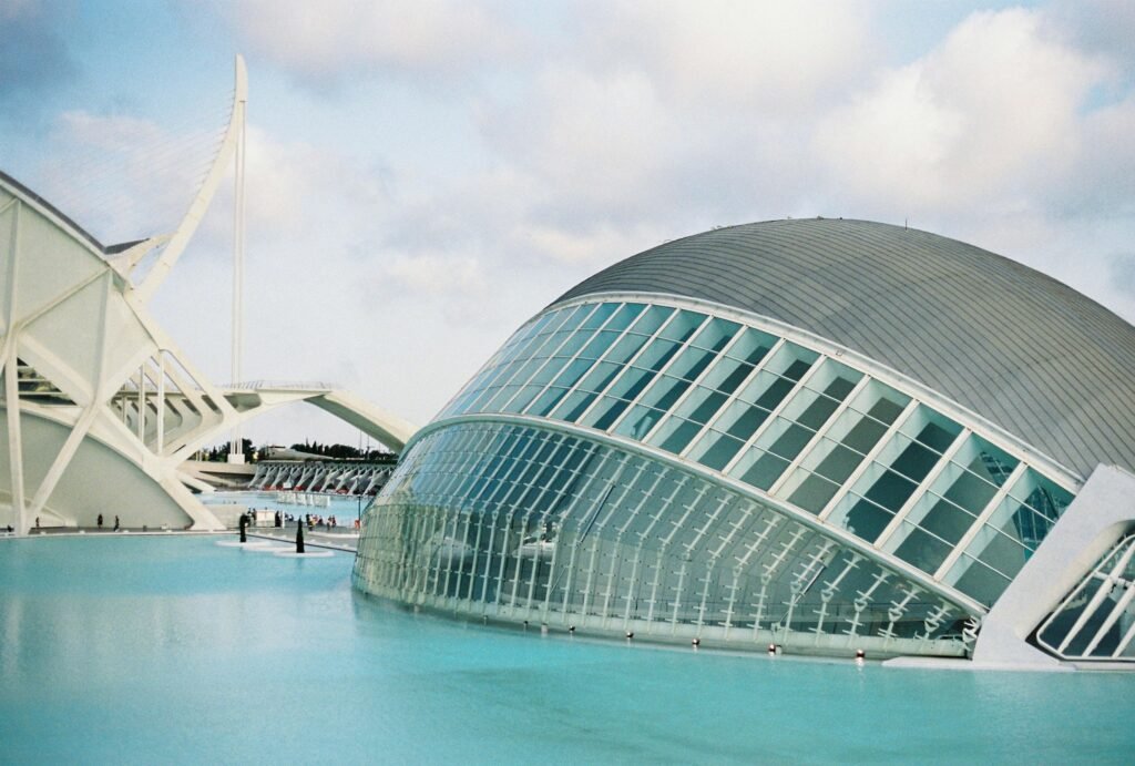 Modern architecture of the Hemisferic building in Valencia, Spain, reflecting in a tranquil pond.